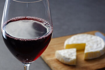Glass of Wine with camembert cheese on the wooden cutting board on the table
