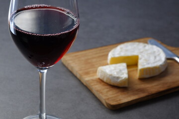Glass of Wine with camembert cheese on the wooden cutting board on the table