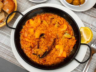 National Spanish dish is paella with seafood, cooked in a pan of rice with saffron, with the addition of the gifts of the sea. ..Decorated with a slice of lemon