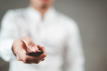 A businessman in a white shirt is pressing a remote control, pointing it at your face.