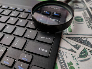 Closeup magnifying glass,banknote and keyboard business online concept