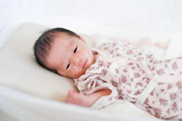 A 7-day-old Japanese baby sleeps soundly on a baby bed. Soft light gently wraps the newborn, capturing a quiet and pure moment of early life. Great for parenting, newborn care, or lifestyle content.