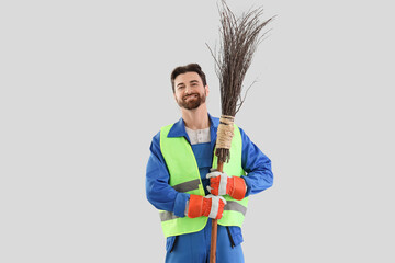 Male scavenger with broom on light background