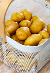 Pile of clean young potato tubers in basket. Fresh vegetables.