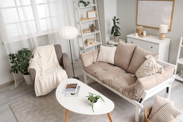 Interior of light living room with armchair, lamp and sofa