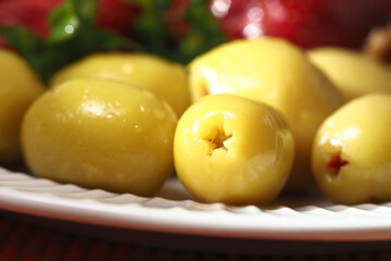 Fresh green olives arranged on a white plate for culinary use