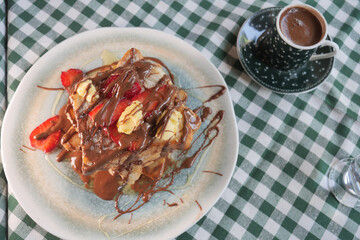 Delicious stack of French toast topped with fruits and chocolate sauce