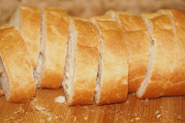 Freshly sliced bread on a wooden cutting board in a kitchen