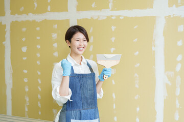 石膏ボードにパテを塗るDIYする女性