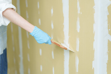 石膏ボードにパテを塗るDIYする女性