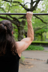 Man exercising on pull-up bar in outdoor park setting