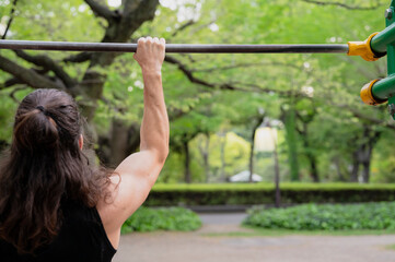 Man exercising on pull-up bar in outdoor park setting