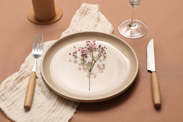 Beautiful table setting with gypsophila flowers on brown background, closeup