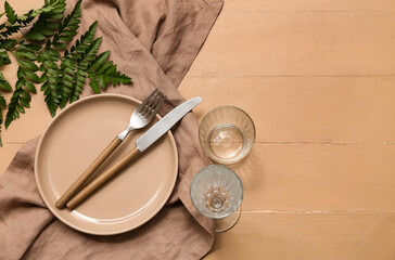 Fototapeta na wymiar Beautiful table setting with fresh green leaf on beige wooden background