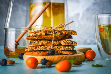 Flax and sesame seed crackers on a wooden board with sea buckthorn tea with honey, blueberries and kumquat on a blue background. Healthy, vegetarian breakfast. High quality photo