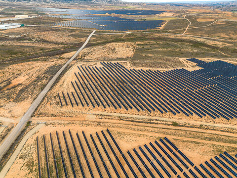 Drone view of solar energy fields in Zaragoza, Spain, capturing clean energy technology in large-scale integration with rural environment and natural topography.