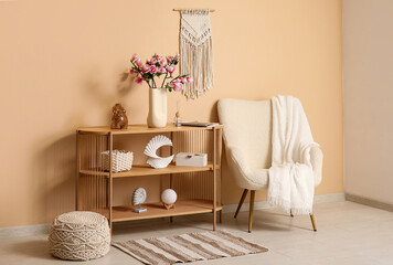 Vase with blooming magnolia flowers on console table near stylish armchair in living room