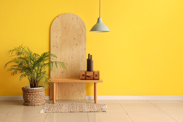Bench, houseplant and folding screen near yellow wall in modern hall