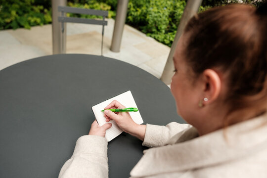 Businesswoman writing notes outdoors in a modern urban setting