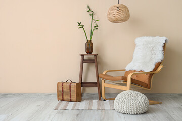 Interior of living room with comfortable chair, pouf and stool near beige wall