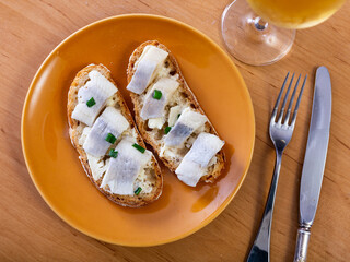 Appetizing sandwich with herring fillet and butter served on plate