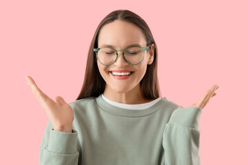 Beautiful young happy woman in new eyeglasses on pink background