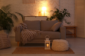 Interior of dark living room with sofa, table and glowing lamps