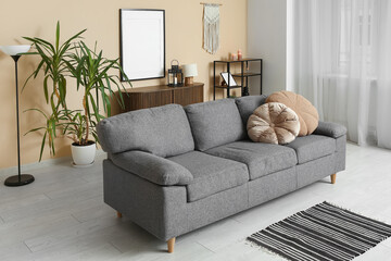 Interior of light living room with sofa near beige wall