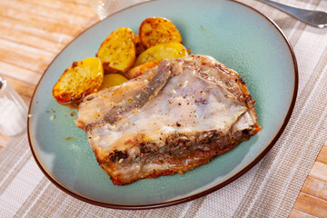 Appetizing homemade baked pork ribs with vegetable garnish of sliced fried potatoes.