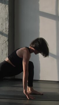 Vertical video. Body stretch. Gymnastic stand. Athletic woman in activewear practice pilates workout exercise yoga asana pose flexibility training on sport mat in gym fitness studio indoors.