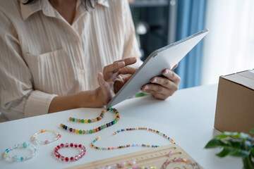 Mature asian woman business owner E-commerce online orders with tablet entrepreneurship jewellery accessories handcraft Cardboard Box.