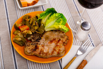 Delicious juicy roast pork with stewed vegetables, garnished with lettuce leaves on a plate