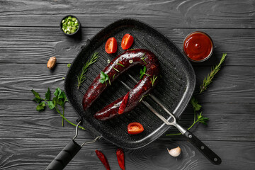 Grill pan with tasty blood sausage on dark wooden background