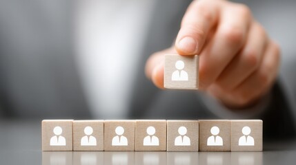 Individual placing wooden block on group of people representing teamwork and technology in business capability matrix