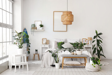 Interior of light bedroom with surfboard, soft bench and plants