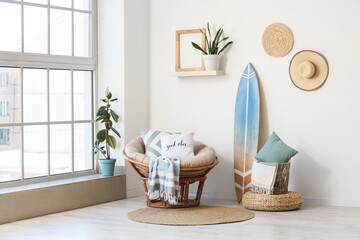 Interior of light room with surfboard, armchair and pillows