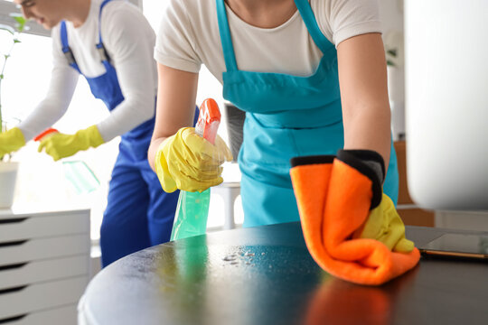 Female janitor cleaning desk in office, closeup
