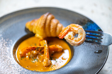 Delicious golden-brown croissant filled with creamy cheese and savory ingredients served alongside...