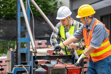 Two construction workers wea safety helmets and reflective vests inspecting equipment on a busy...