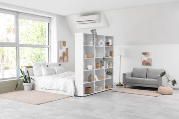 Interior of light room with shelf unit, bed and sofa