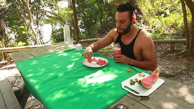Man on picnic in park. Making and drinking watermelon juice.