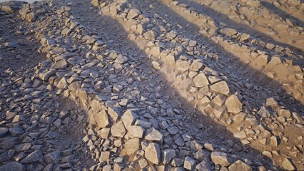 Fototapeta premium Rocky tracks, diagonal grooves cut through small rocks, textured surface, sandy hues