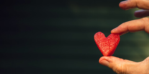 Summer seasonal food. Juicy red watermelon slice cut in heart shape outdoors summertime holidays sunbeams. Concept of enjoying the moment in fresh air. Sustainable calm lifestyle pastoral life