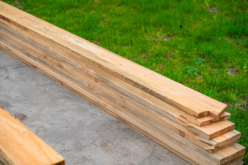 Wooden boards for construction stacked on a background of green grass, close-up
