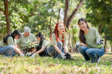 Fototapeta premium Young Asian Volunteers Group Planting Tree for Environmental Conservation, Eco-Friendly Group Activity: Teamwork in Tree Planting