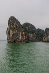 Naklejka premium Ha Long Bay littered with mountains and Rock cliffs popping out of the ocean, lush green mountains in Vietnam