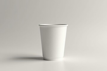 A simple white disposable cup sits on a plain surface against a neutral background