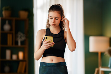 Young woman is wearing wireless headphones using her smartphone