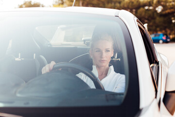 Woman driver driving a white sports car on the road
