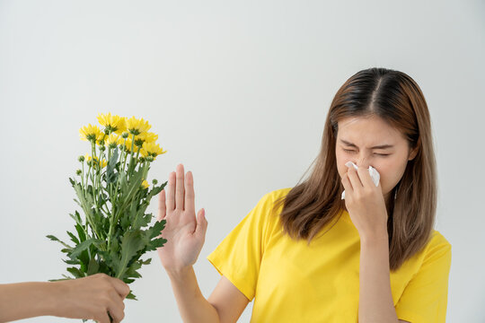 Pollen Allergies, asian young woman sneezing in a handkerchief or blowing in a wipe, allergic to wild spring flowers or blossoms during spring. allergic reaction, respiratory system problems